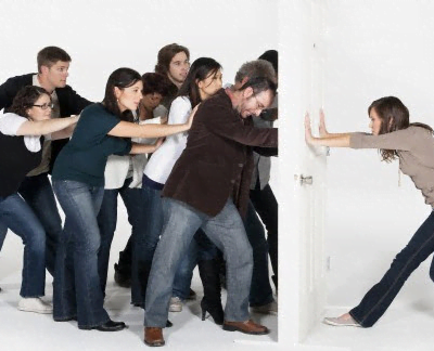 Employees using overt resistance to push against door being held by team lead