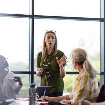 Business meeting with a diverse team, led by a woman leader, discussing strategy and collaboration in a corporate setting