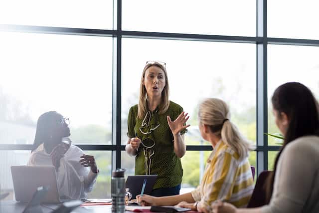 Business meeting with a diverse team, led by a woman leader, discussing strategy and collaboration in a corporate setting